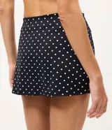 Short pollera deportivo negro con estampa de lunares blancos, confeccionado en microfibra con cintura alta y short interno integrado.