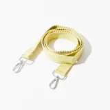 Correa de tela tejida color verde claro, con mosquetones metálicos plateados en los extremos.