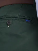 Pantalón de gabardina color azul marino, de corte recto y estilo clásico, con cierre de botón y cremallera, y trabillas para cinturón.