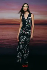 Vestido largo negro con estampado de palmeras blancas y detalles en verde y rosa, de corte al cuerpo, con escote en V y frunce diagonal en el centro.