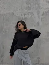 Conjunto deportivo compuesto por un buzo negro de corte cropped con costuras a la vista y un pantalón jogging gris de tiro alto, corte holgado y costuras verticales decorativas.