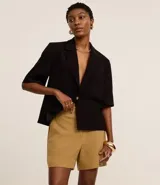 Bermuda roja de poliéster con cintura elástica, bolsillos laterales y cierre con cremallera y botones.