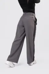 Pantalon de vestir gris con detalle de franjas laterales negras y etiqueta de marca Dolce en el bolsillo trasero.