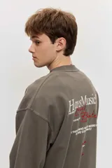 Buzo de friza color gris oscuro, de corte oversize, con cuello redondo y diseño liso. Cuenta con un pequeño bordado en el pecho.