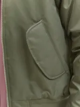 Campera tipo bomber color verde oliva, con cierre frontal de doble dirección, cuello, puños y ruedo acanalados. Presenta bolsillos laterales con solapa y forrería interna.