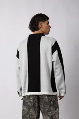 Sweater de punto con diseño a rayas verticales en color beige y blanco, de corte holgado y cuello polo abierto. Presenta un logo bordado en el centro del pecho.