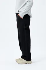 Pantalón jean negro de corte amplio y estilo carpenter, con tiro medio, bolsillos utilitarios y presillas laterales.