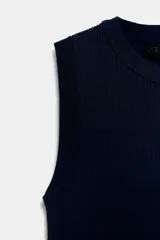 Top crop de tejido de punto color beige claro, con cuello redondo y manga sisa. Presenta acabados en rib en el cuello, sisas y bajo.