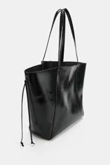 Bolso tipo shopper de efecto arrugado y acabado brillante en color negro, con detalles fruncidos en el centro, cordones colgantes en los laterales y doble asa para el hombro.