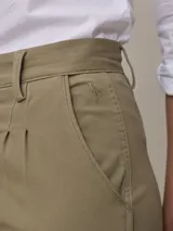 Pantalón color beige de corte recto, con pinzas en la cintura, bolsillos laterales y tobillos ajustados.