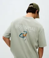 Remera de algodón con corte relajado, cuello redondo y mangas cortas. Presenta una estampa trasera con ilustración de mosquetones y el texto Essential, junto con una estampa frontal discreta.