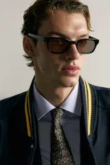 Cazadora bomber estilo universitario, de corte relaxed fit y tejido técnico azul marino, con cuello, puños y dobladillo de rib elástico a rayas amarillas. Cuenta con bolsillos delanteros de plastrón y cierre frontal con botones a presión.