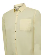 Camisa de manga larga RKF modelo Galiton, confeccionada en popelina de algodón orgánico color amarillo. Presenta cuello camisero, cierre frontal con botones de madera, bolsillo en el pecho con logo bordado y mangas ajustables.
