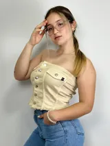 Top strapless color beige con botones plateados al frente y dos bolsillos pequeños.
