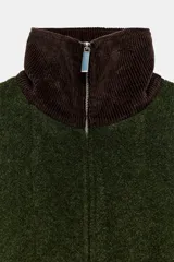 Capa de punto color verde oscuro con cuello subido de pana en color marrón. Presenta cierre frontal con cremallera metálica y diseño holgado.