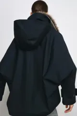 Trench corto de corte recto con capucha y cuello desmontable efecto pelo. Presenta cierre frontal con botones, bolsillos laterales y mangas largas con trabillas en los puños.