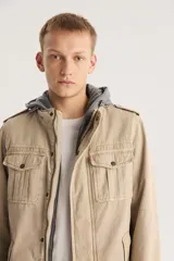 Campera color beige con capucha gris, cierre frontal con cremallera y botones a presión, cuatro bolsillos frontales con solapa y charreteras en los hombros.