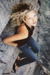 Top chaleco negro satinado con cuello halter, espalda descubierta y cierre frontal con cremallera y botón a presión ocultos por solapa.