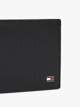 Billetera compacta Tommy Hilfiger de cuero vacuno negro con textura grabada en relieve. Cuenta con el logo distintivo de la marca aplicado en la esquina inferior derecha.