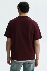 Remera de punto de algodón de peso medio color bordó, con cuello redondo ribeteado, hombros caídos y bajo recto, de corte relajado.