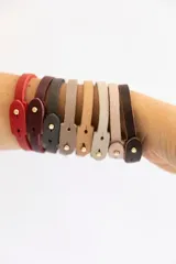 Pulsera de cuero vacuno color borgoña con broche dorado, pulsera de cuero vacuno color rosa pálido, pulsera de cuero vacuno color gris con la palabra "Guiller" grabada y pulsera de cuero vacuno color verde oscuro con la palabra "Enzo" grabada.