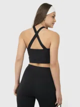 Top deportivo negro con diseño de cuello halter y tirantes cruzados en la parte frontal. Cuenta con sujetador integrado y almohadillas removibles, ofreciendo soporte medio.