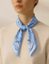 Pañuelo cuadrado de satén con estampado abstracto en tonos celestes y azules. Presenta un diseño fluido y elegante, ideal para usar anudado al cuello.