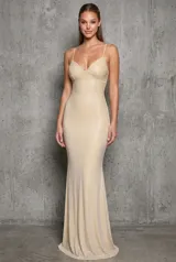 Vestido largo de fiesta color beige con acabado brillante, corte sirena y tirantes finos ajustables. Cuenta con copas estructuradas en el busto y pedrería en degradé.