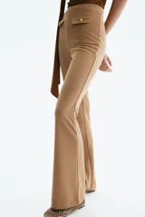Pantalón acampanado de punto roma en color tostado, con cintura elástica oculta y solapas de bolsillo decorativas con botones dorados en la parte frontal.