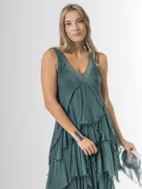 Vestido largo negro de seda italiana con diseño sin mangas de bretel ancho y escote en V profundo con detalles de paillettes plateados. Presenta múltiples capas con volados y bordes deshilachados que aportan movimiento y una caída fluida.
