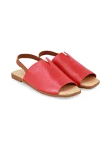Sandalia de cuero graneado color rojo, con diseño destalonado, tira elástica marrón en el talón, empeine cubierto con detalle de abertura central y suela plana.