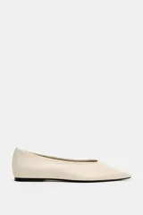 Zapato plano tipo bailarina confeccionado en piel de color beige, con escote redondo y acabado en punta fina.