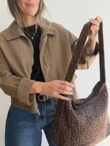 Bolso tipo hobo con estampado animal print y acabado efecto gamuza. Cuenta con asa regulable y cierre superior con cremallera.