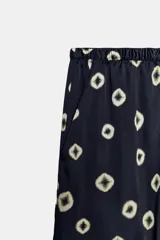 Pantalón de tiro medio con cintura elástica y bolsillos ocultos en costura. Presenta un diseño de corte recto con dobladillo ancho en el bajo y un estampado geométrico sobre fondo oscuro.