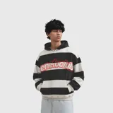 Hoodie de corte holgado con diseño de rayas horizontales anchas en blanco y negro. Presenta una capucha integrada y un bolsillo frontal tipo canguro. En el pecho, destaca un estampado gráfico con el texto 'eneroclub' en letras rojas con contorno blanco.