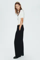 Camiseta blanca de manga corta y corte slim fit, con escote redondo ribeteado en negro, detalle de frunce en el centro del pecho y un pequeño lazo negro decorativo.