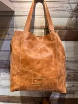 Bolso tipo shopper de cuero con acabado texturizado en tono metalizado claro. Cuenta con doble asa de hombro y etiqueta de cuero con logo grabado en la parte inferior frontal.