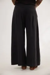 Pantalón de corte ancho y tiro alto, color negro, con diseño de pinzas en la parte frontal y cierre con botón y cremallera.