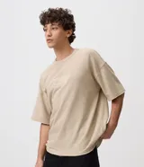 Remera de manga corta color beige, con cuello redondo y bordado frontal con motivo gráfico y texto 'Open Air'.