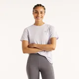 Remera deportiva New Balance Athletics de color lila, confeccionada en tejido de malla transpirable, con cuello redondo, mangas cortas y logo reflectante de la marca en el pecho.