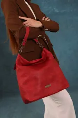 Cartera tipo bandolera de gran tamaño, confeccionada en cuero sintético con acabado desgastado. Cuenta con una asa corta fija, una correa larga regulable y extraíble, y una placa metálica con la marca en la parte frontal.