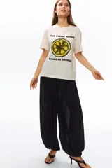 Remera de punto suave de algodón, color beige, con hombros ligeramente caídos y cuello redondo ribeteado acanalado. Cuenta con estampa frontal de la banda The Stone Roses con ilustración de un limón y texto.