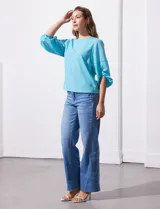 Blusa de gasa con estampado geométrico en tonos negro, gris y celeste. Tiene cuello redondo y mangas 3/4 amplias con abertura y botón.