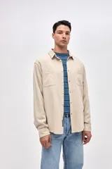 Camisa de corte regular fit confeccionada en algodón, con cuello solapa clásico, cierre frontal con botones y dos bolsillos frontales en el pecho.