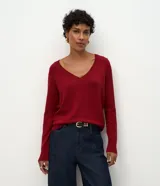 Blusa de punto leve color bordó, con escote en V y mangas largas. Presenta un diseño básico de corte regular con textura acanalada en el cuello.