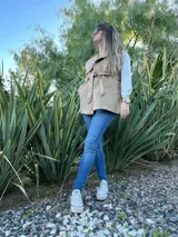 Chaleco color beige con cuello solapa, doble botonadura y lazo para atar en la cintura.