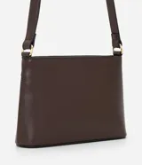 Bolsa bandolera de estructura firme en color marrón oscuro, con cierre de cremallera metálica y correa larga ajustable con hebilla.