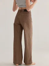 Pantalón de tiro medio alto, color beige, con bolsillos delanteros y traseros. Presenta detalles de atraques y triples costuras en color amarillo. Confeccionado en una mezcla de lino, algodón y viscosa.