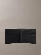 Billetera plegada Calvin Klein confeccionada en piel saffiano color negro. Presenta un diseño clásico con múltiples ranuras para tarjetas y compartimento para billetes, con el logo de la marca grabado en la parte frontal.
