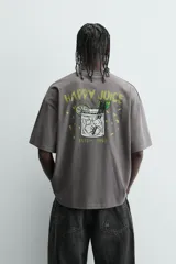 Camiseta de manga corta y cuello redondo, color gris oscuro con efecto lavado. Presenta un pequeño estampado en el pecho con texto en color verde lima.